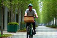 Livreur à vélo devant un paysage urbain vert